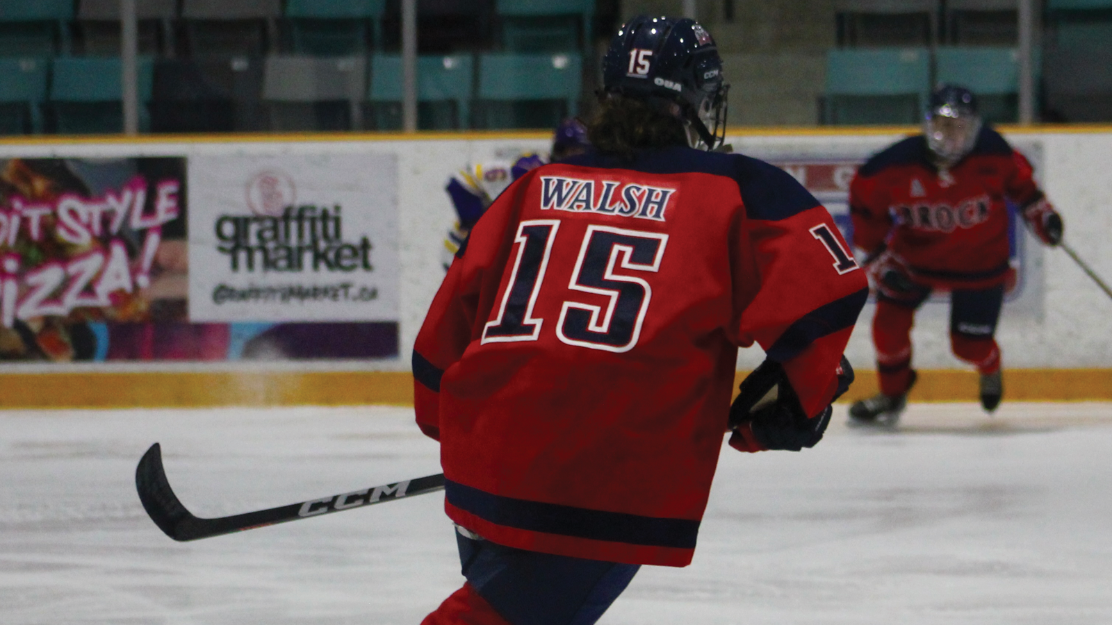 Action photo from behind of Brock women's hockey player Madelyn Walsh skating on the ice