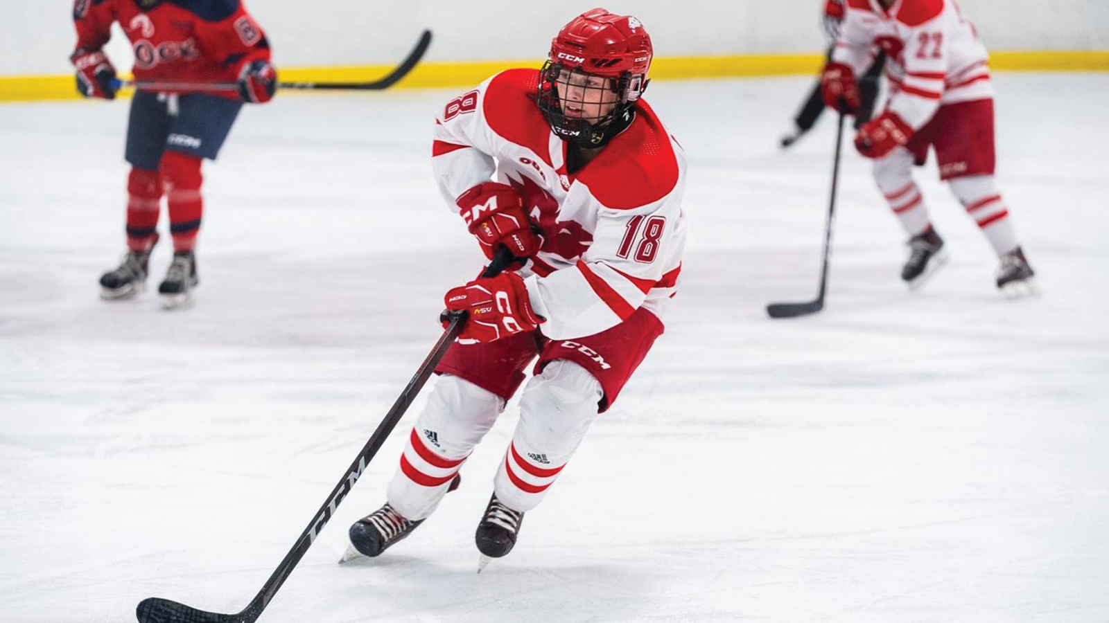 York women's hockey player skating with the puck on her stick with two other players in the background
