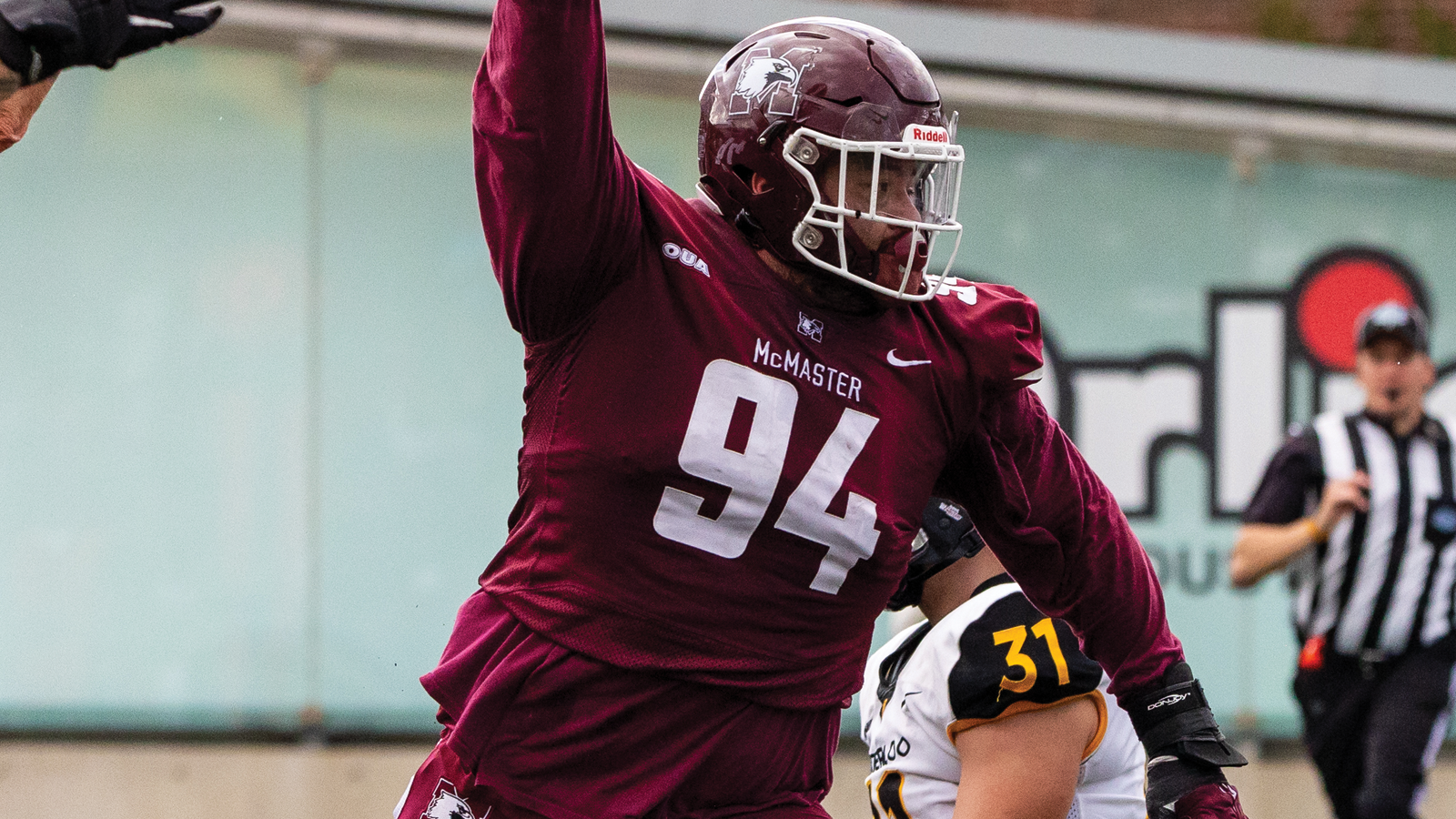 McMaster football player Alex Cheng holding up the ball in celebration during a game