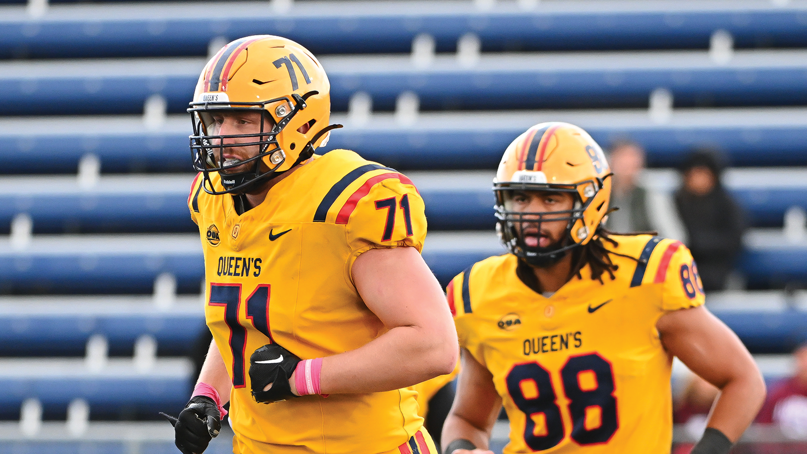 action photo of Queen's football player Nik Henning running onto the field 