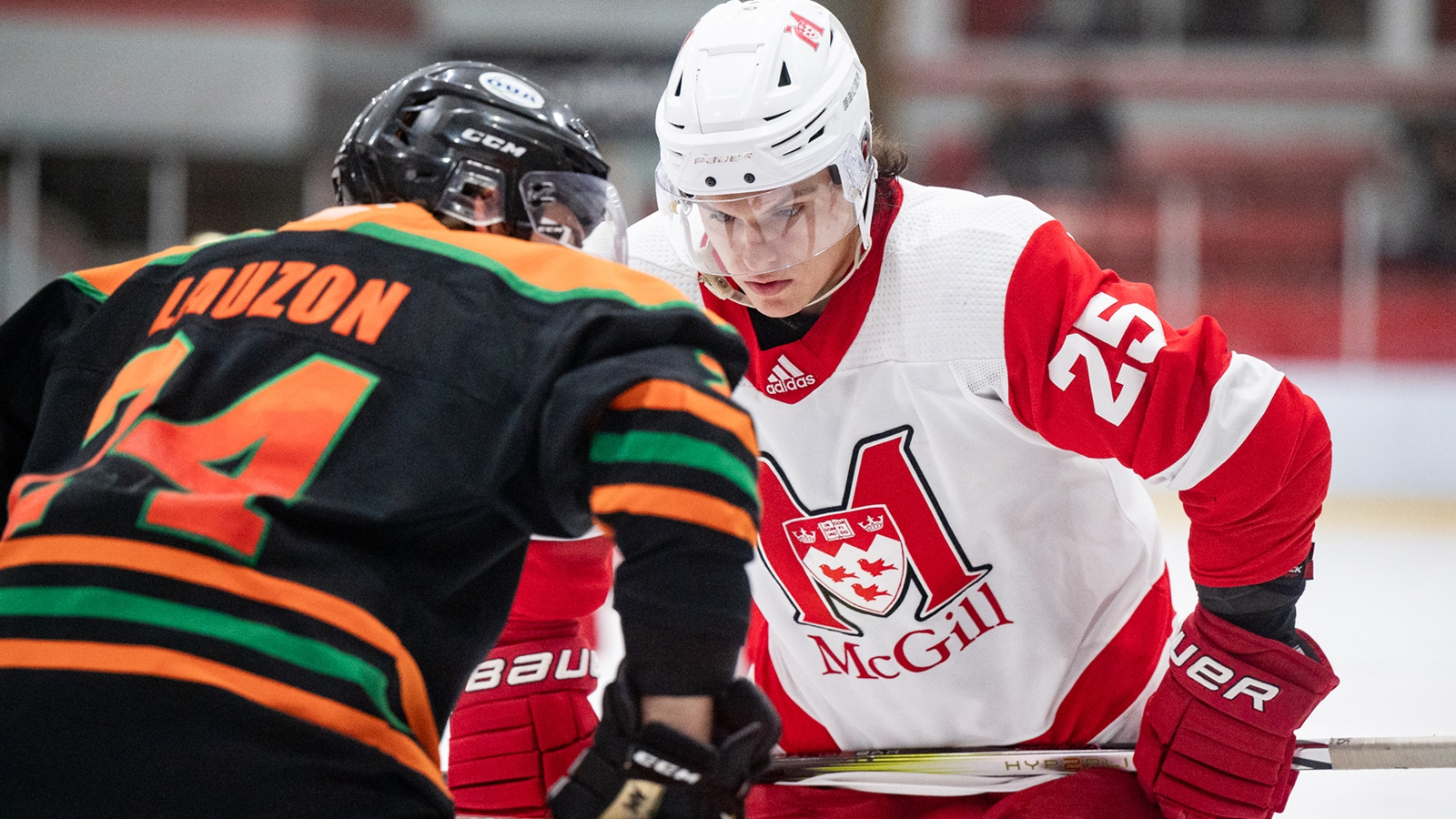 Action photo of a McGill and UQTR men's hockey player, respectively, lining up for a faceoff during a game