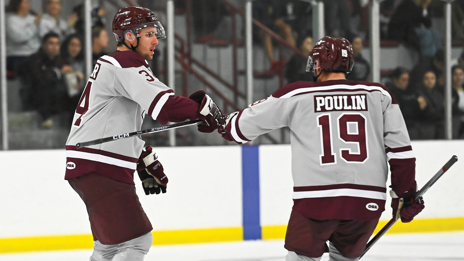 Two Ottawa men's hockey players fist bumping on the ice