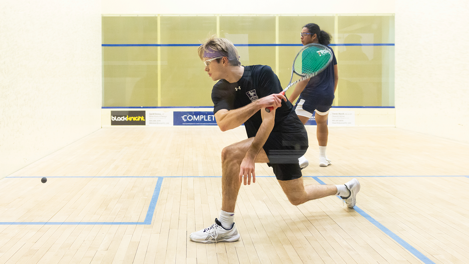 Action photo of a Western men's squash player about to hit the ball 
