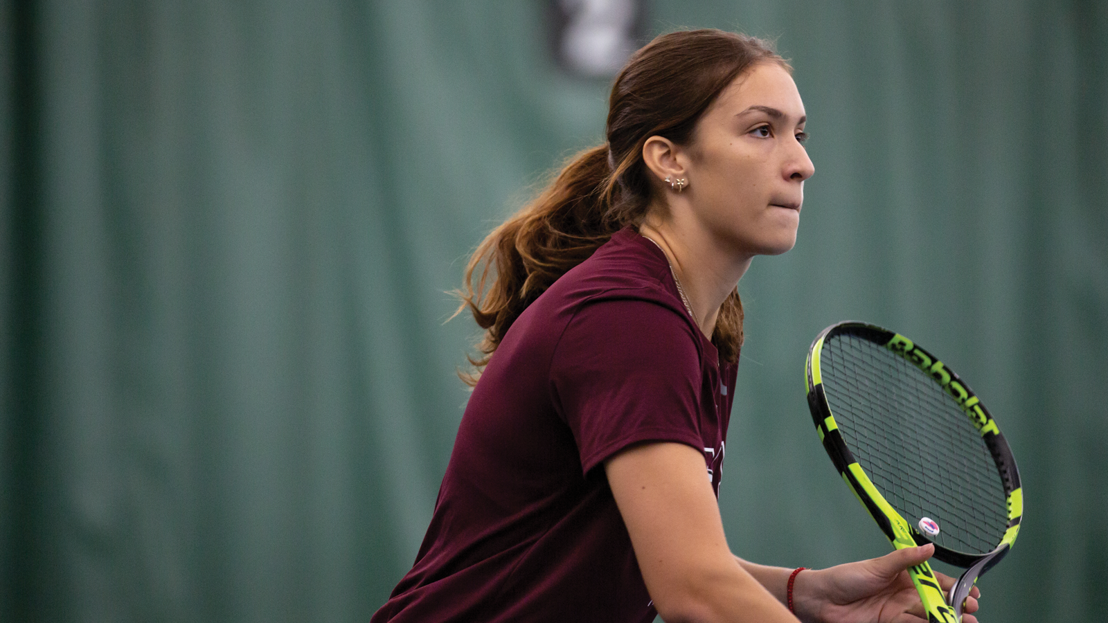 Action photo of McMaster women's tennis player holding her racquet during a point in the match