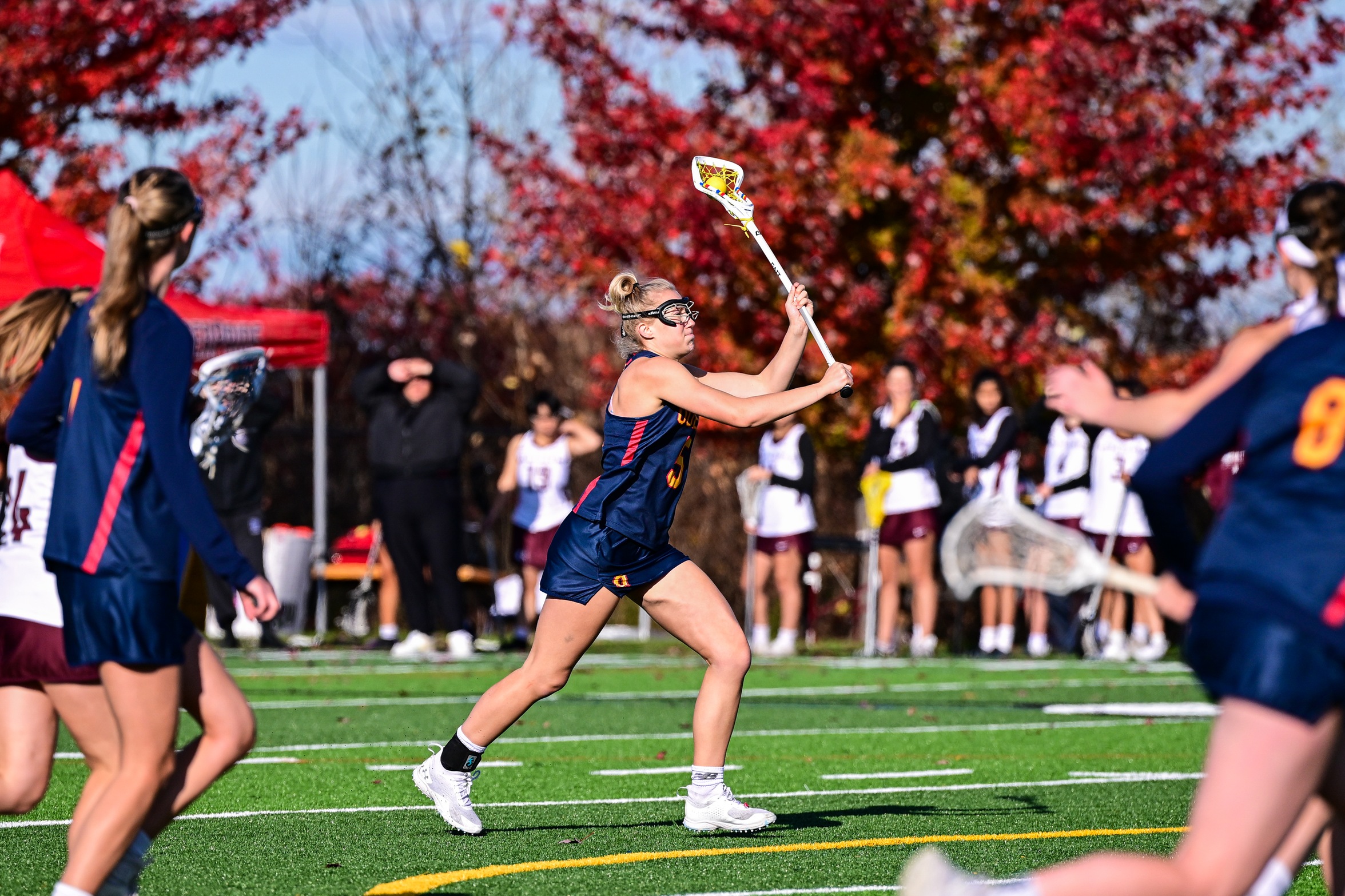 An action photo of a Queen's Gaels women's lacrosse player running with the ball in her stick 
